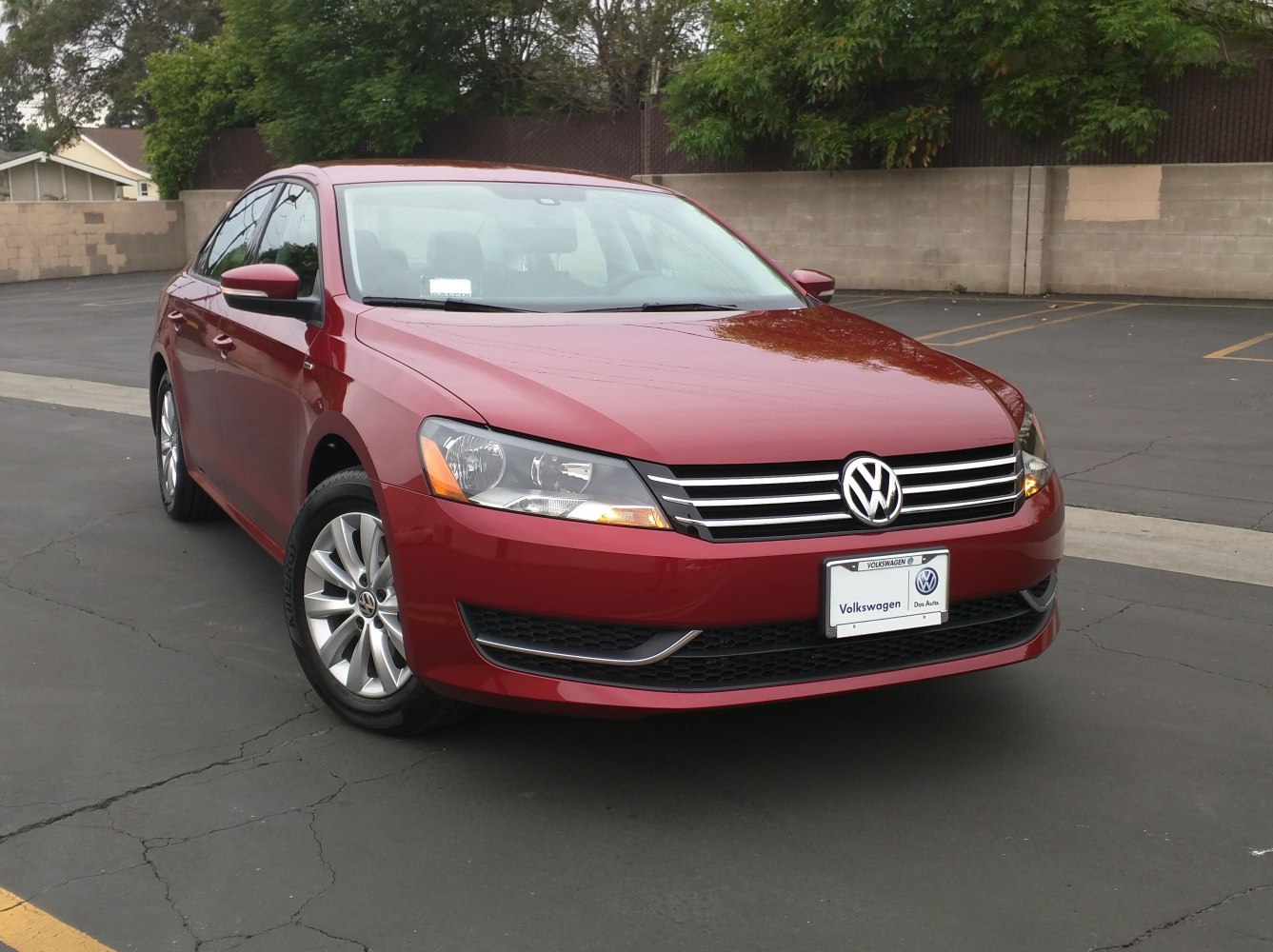 Red sedan front view with chrome horizontal grille and alloy wheels