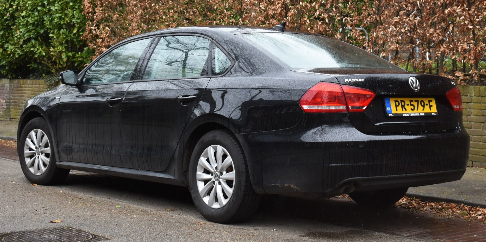Rear side view of a black sedan with alloy wheels and taillights.