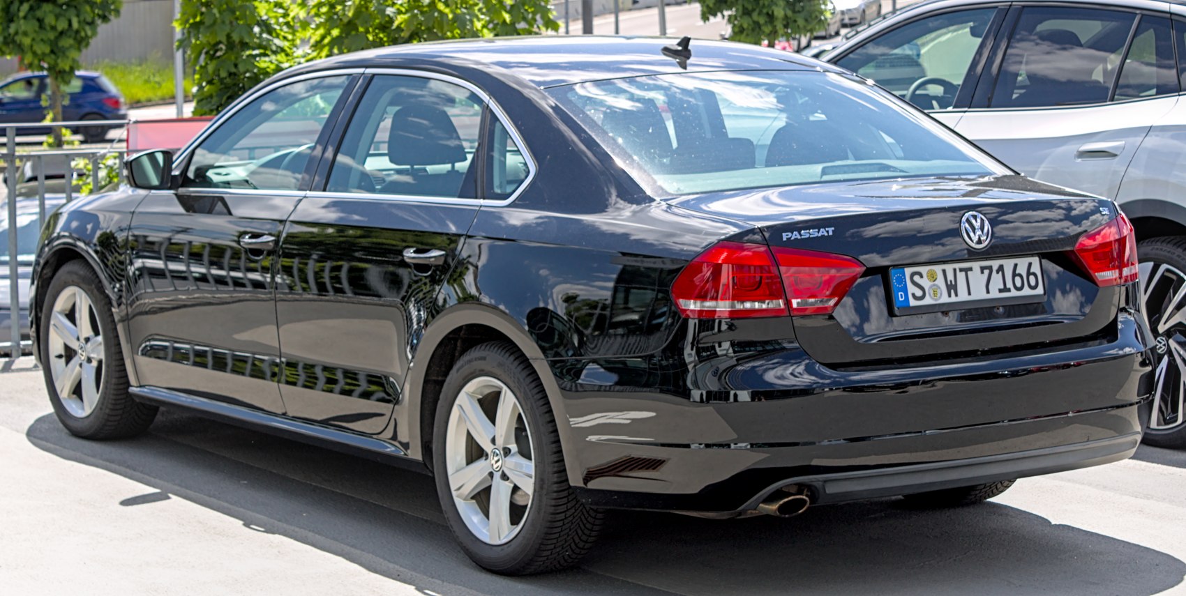 Black sedan rear view with red tail lights and five-spoke alloy wheels