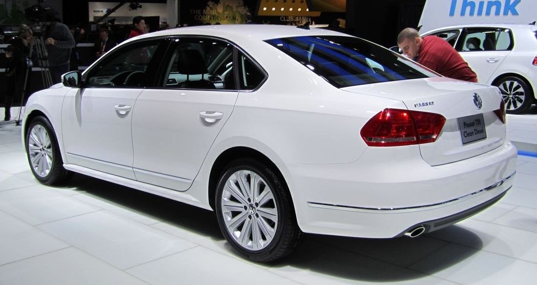 White sedan rear side profile with alloy wheels and exhaust