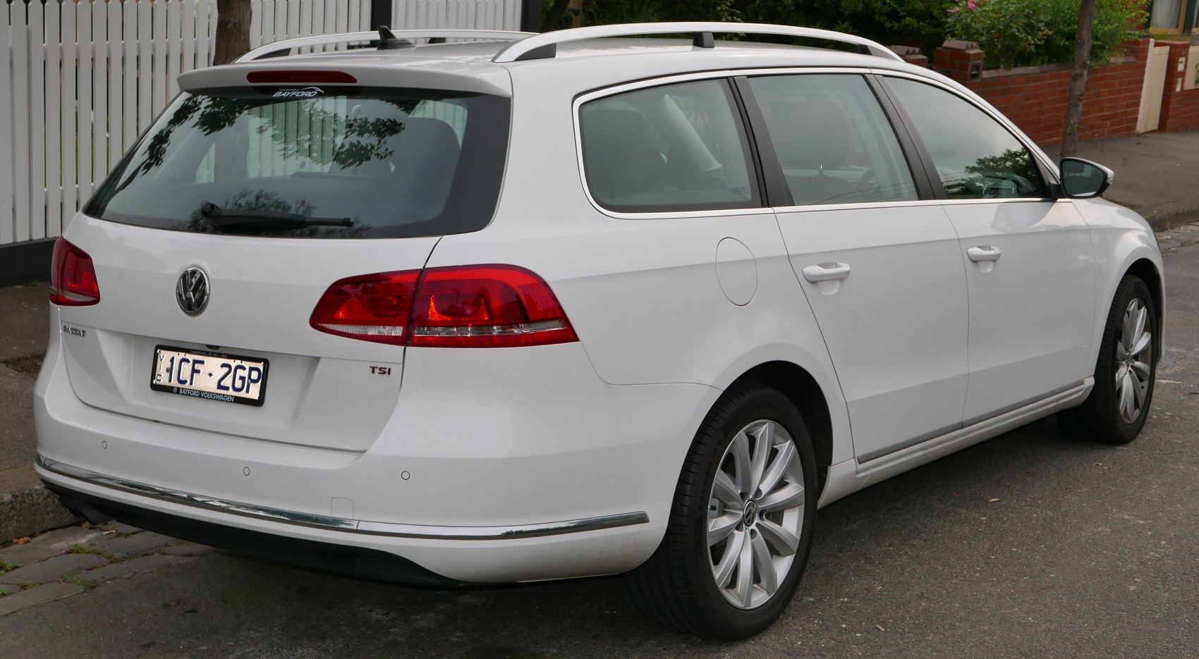 Rear view of white station wagon with roof rails and red taillights.