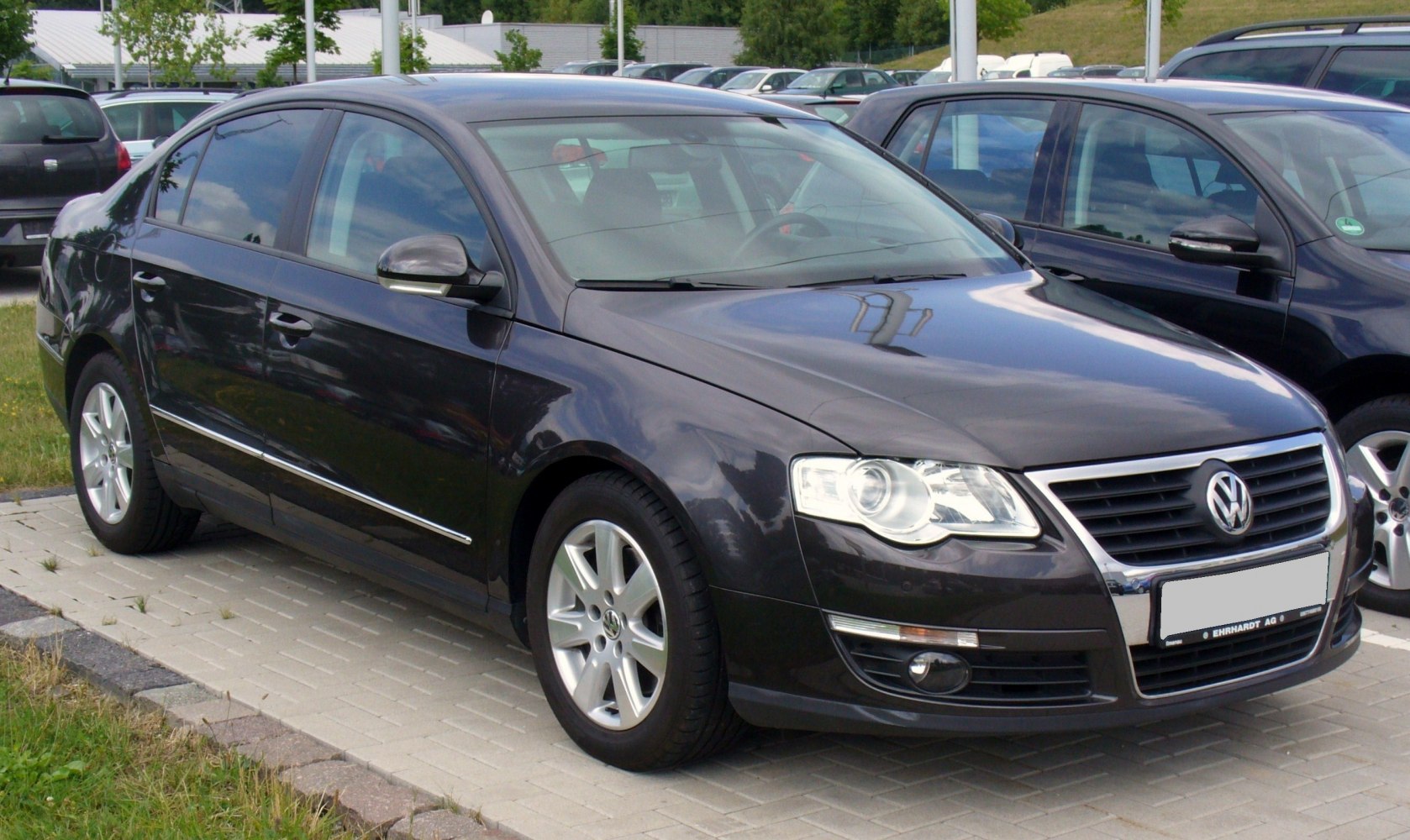 Front-side profile of a mid-2000s sedan with alloy wheels and chrome trim
