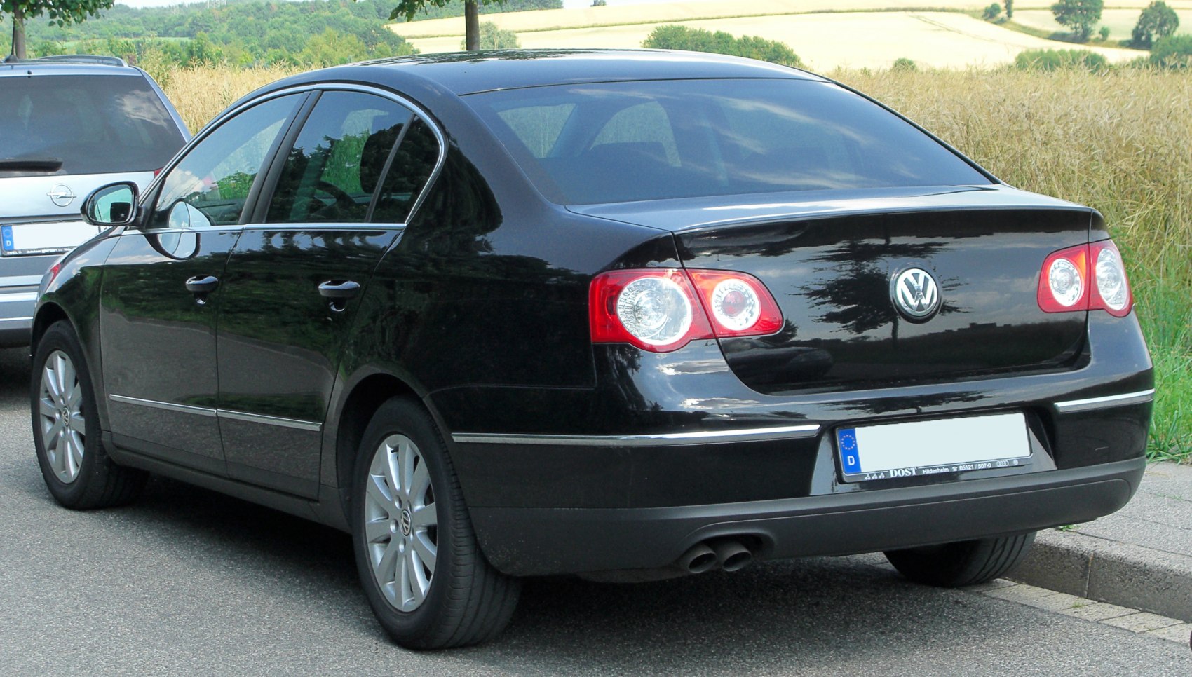 Black sedan rear with round tail lights and dual exhaust pipes