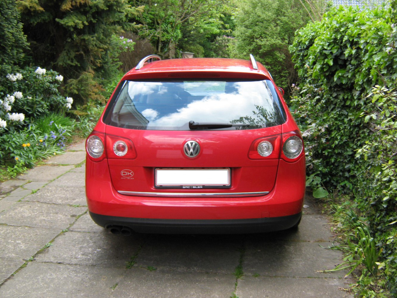 Red station wagon rear with taillights, roof rails, and dual exhaust