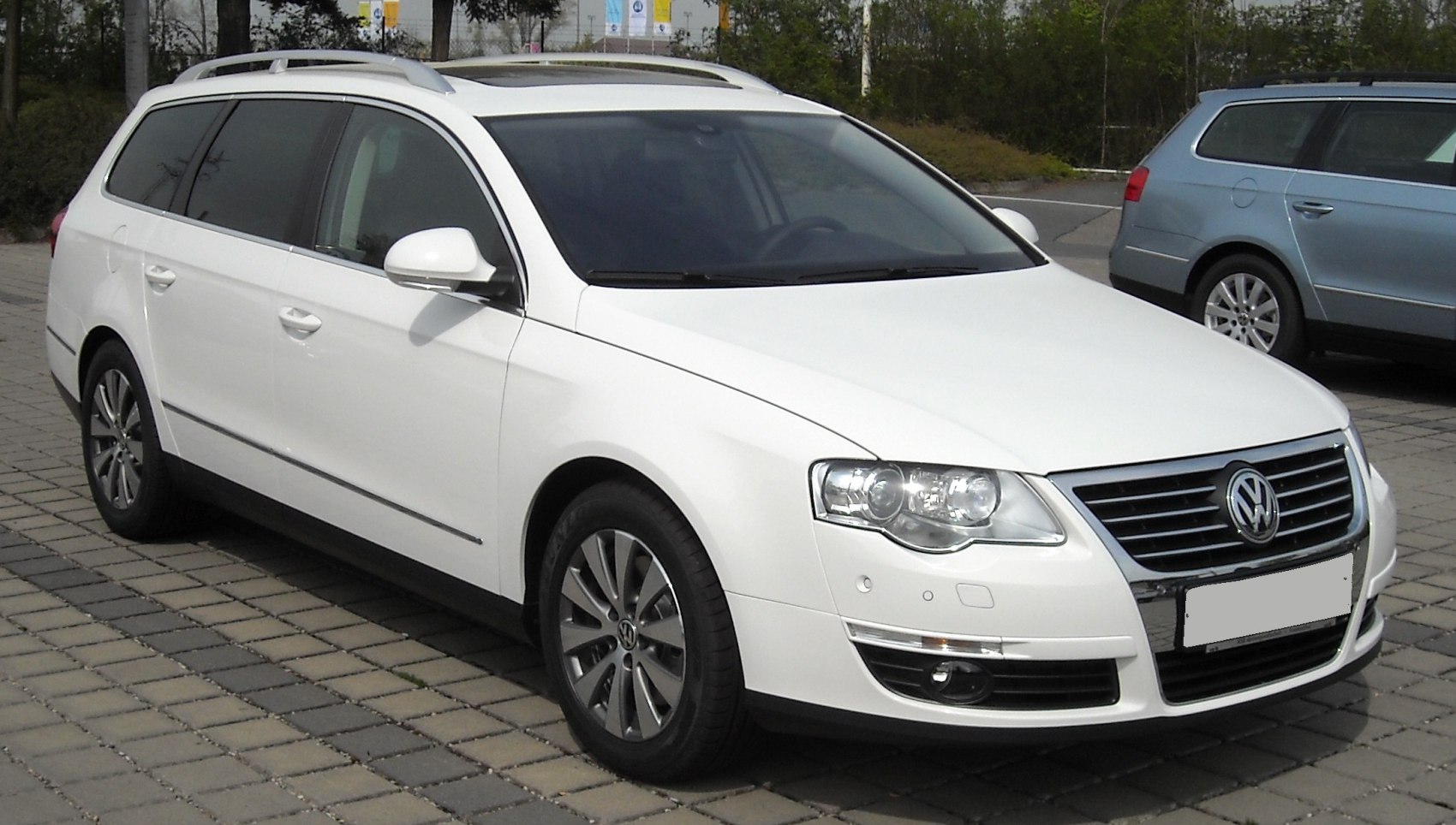 White station wagon with roof rails and sleek headlights, front-side view
