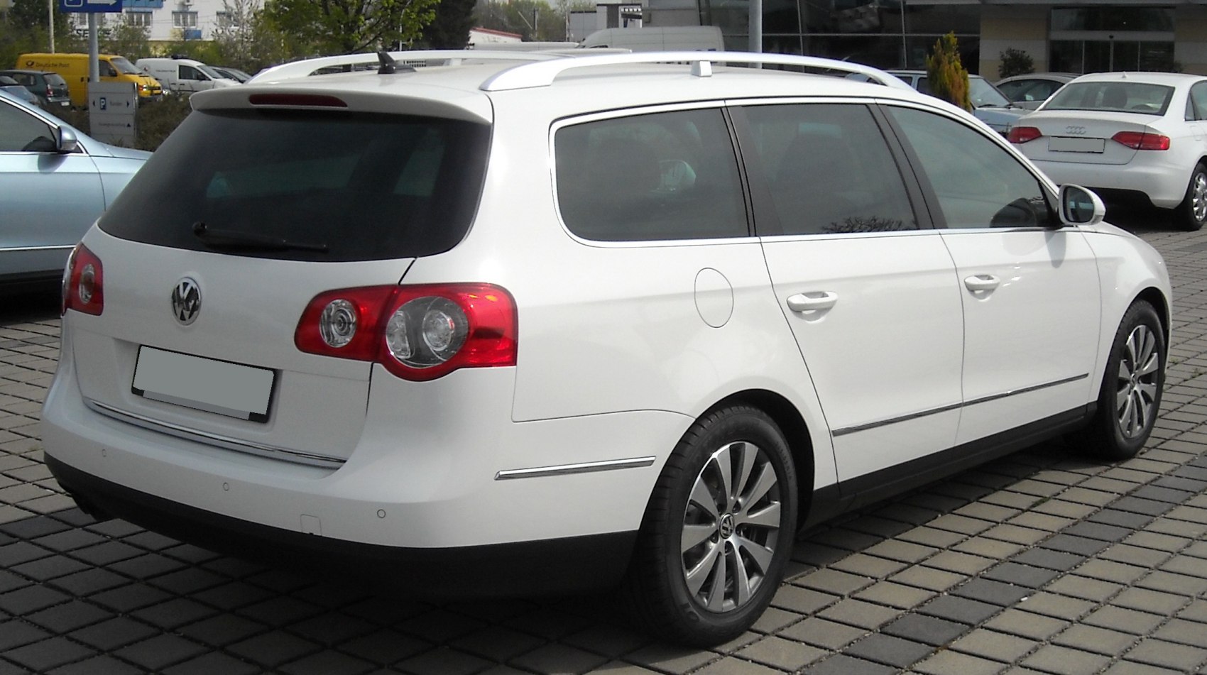 Rear side view of white mid-size station wagon with roof rails and distinct tail lights