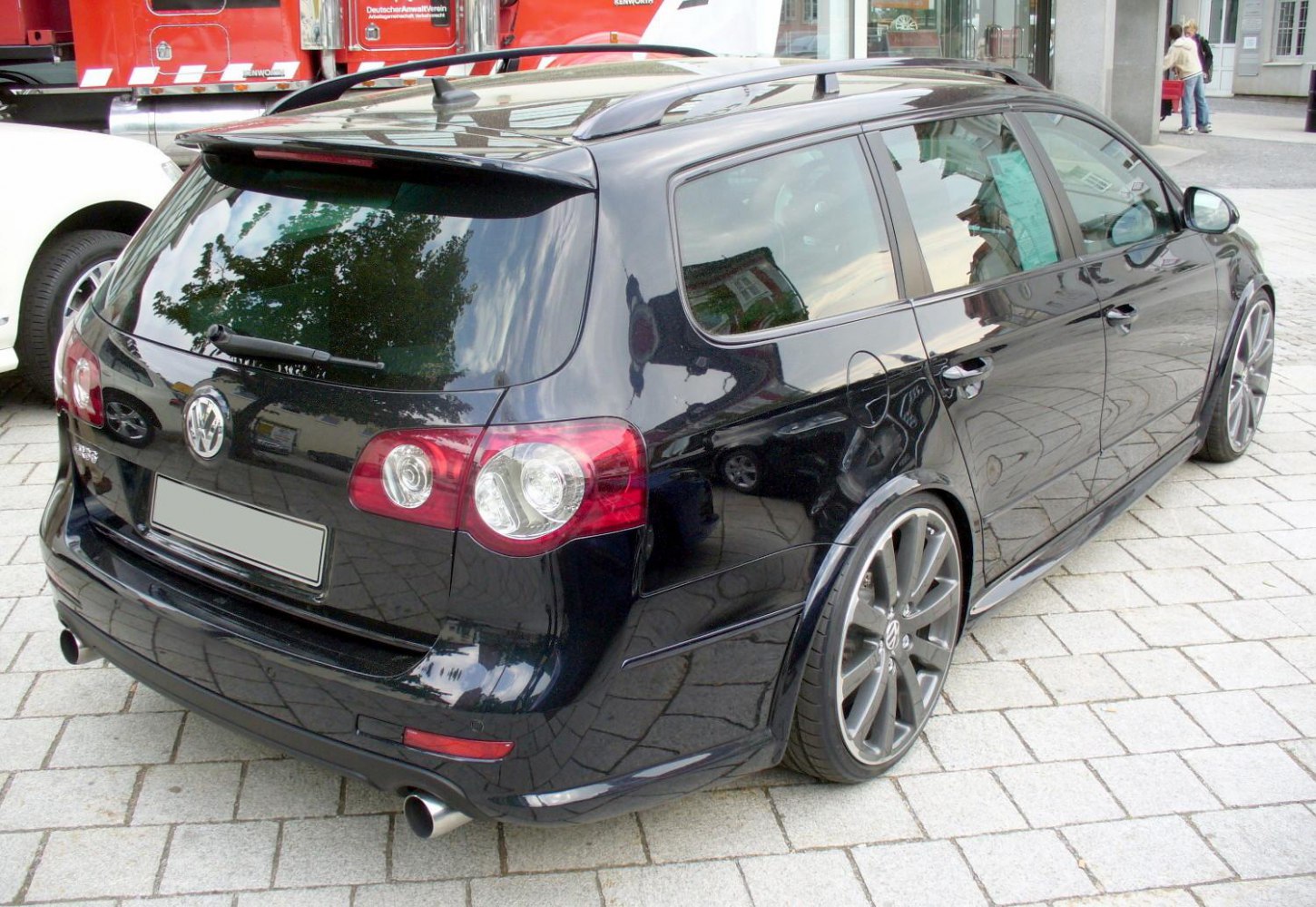 Rear and side view of a black station wagon with sporty alloy wheels and roof rails.