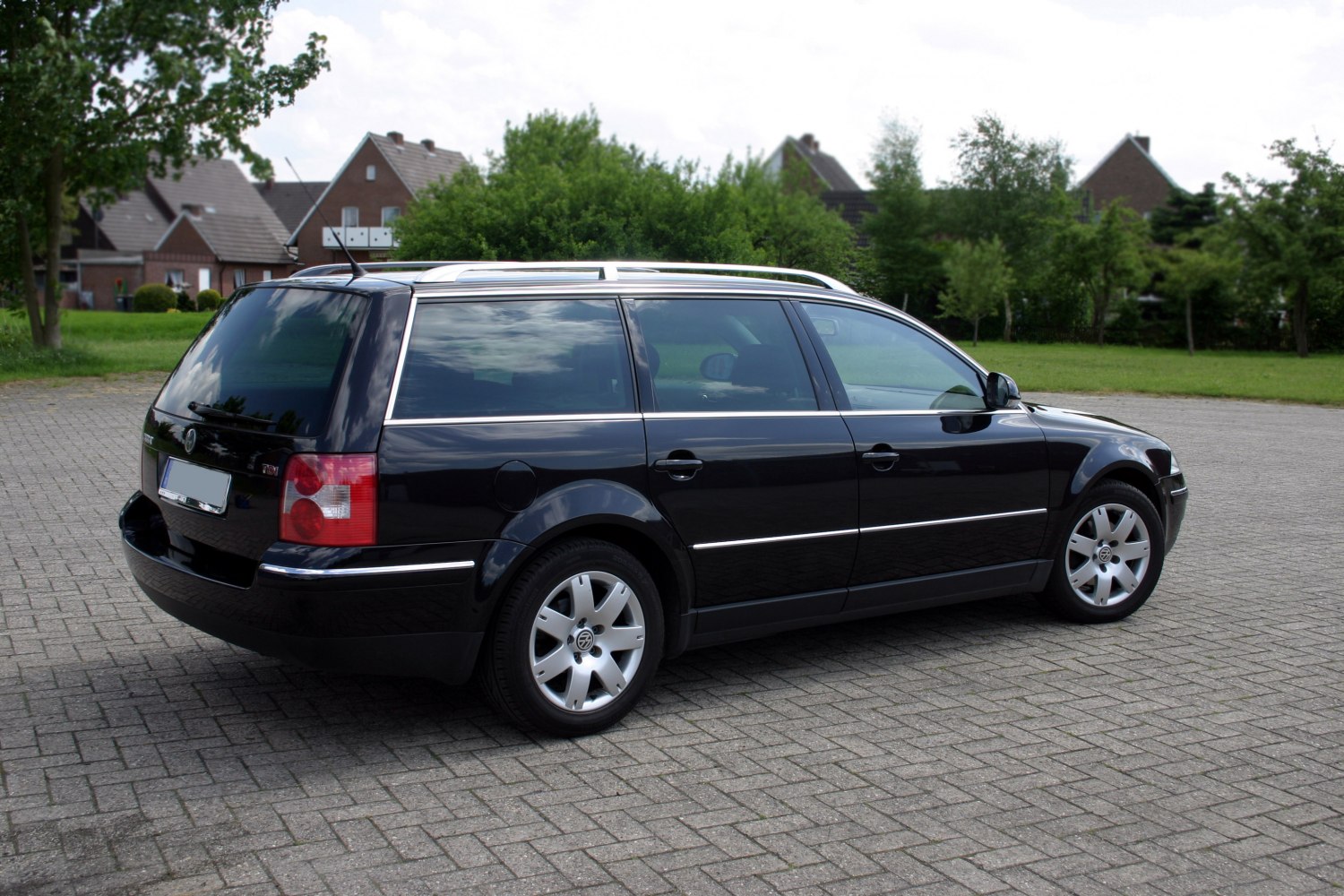 Rear-side view of a black wagon with roof rails and alloy wheels