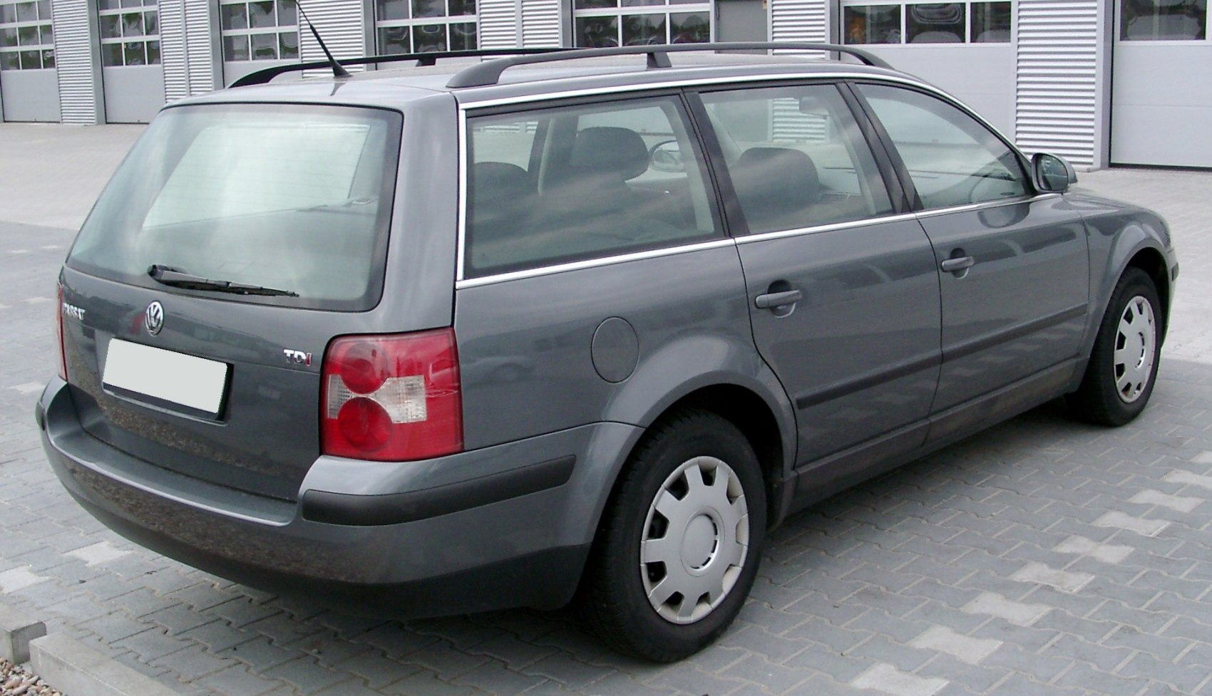 Rear side view of a gray station wagon with roof rails and distinctive taillights