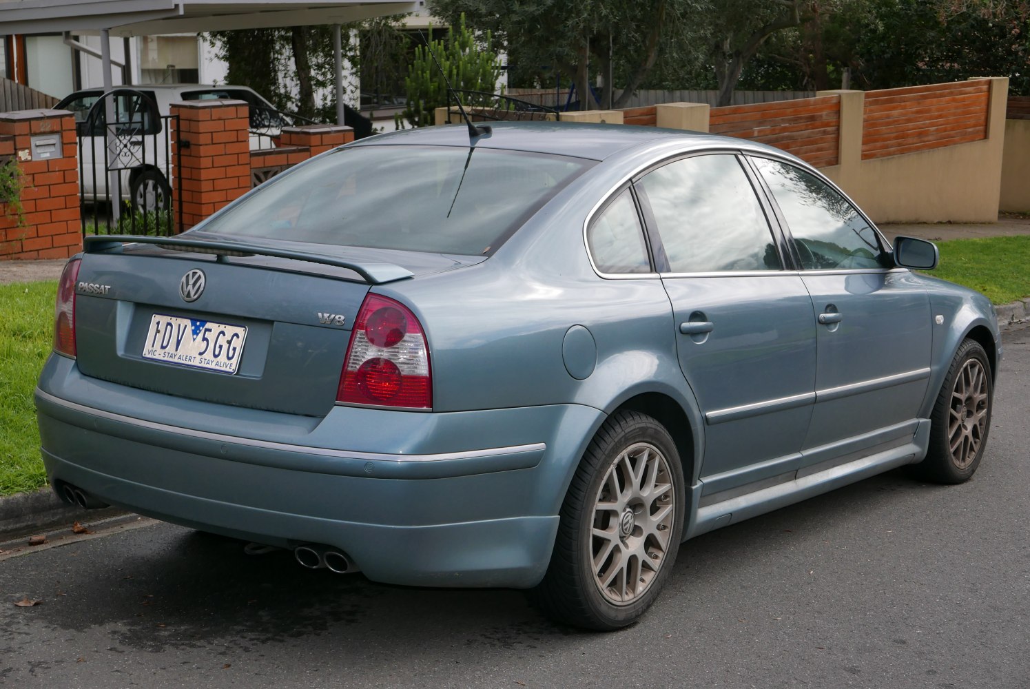 Rear and side view of a sedan with spoiler and dual exhaust pipes