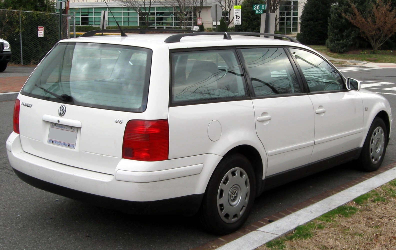 Rear view of white station wagon with tailgate, taillights, roof rails