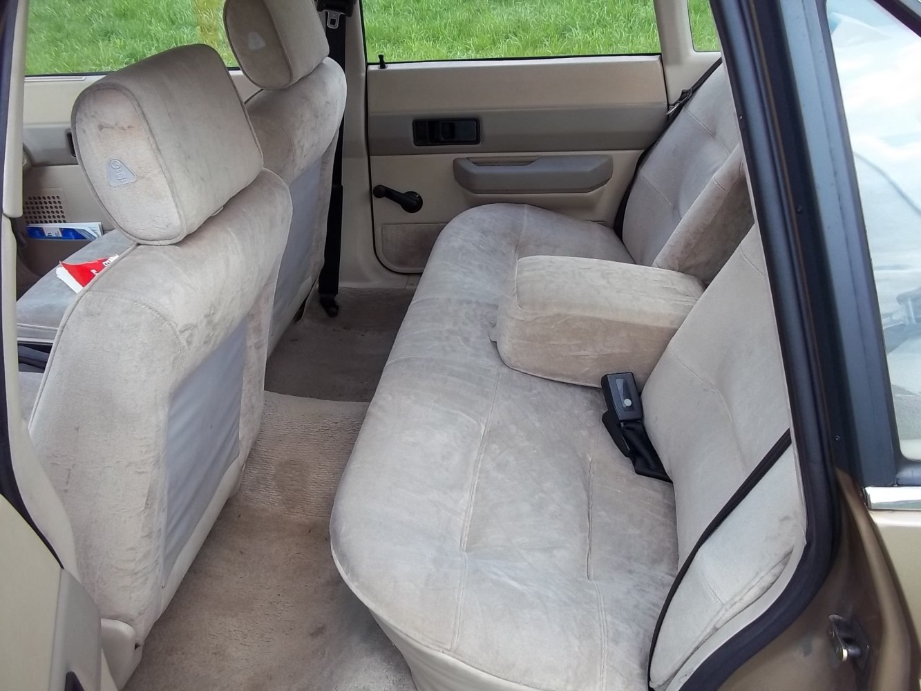 Classic car rear seat with cloth upholstery, armrest, and manual window crank
