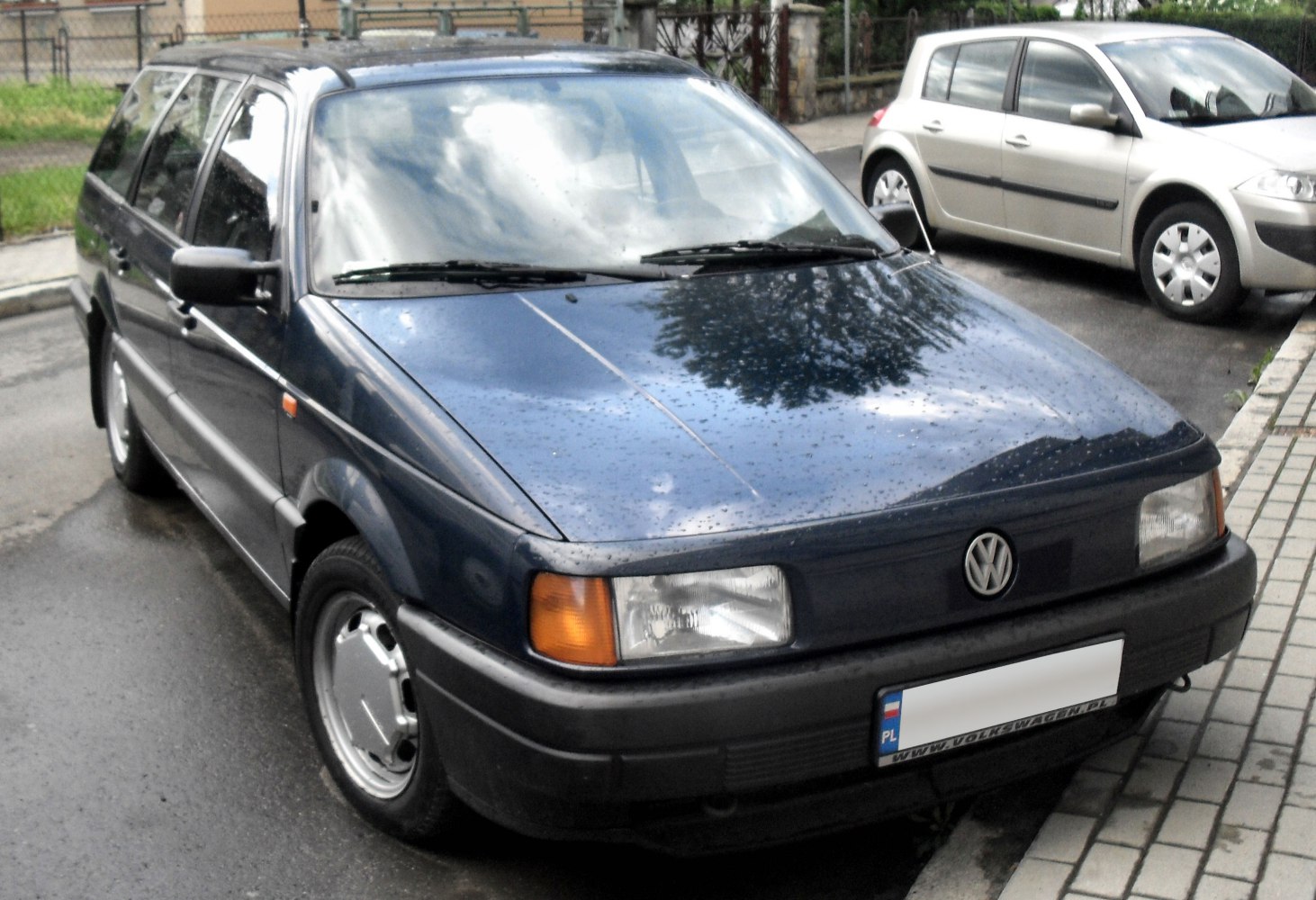 Front view of a blue station wagon with rectangular headlights and wet surface.