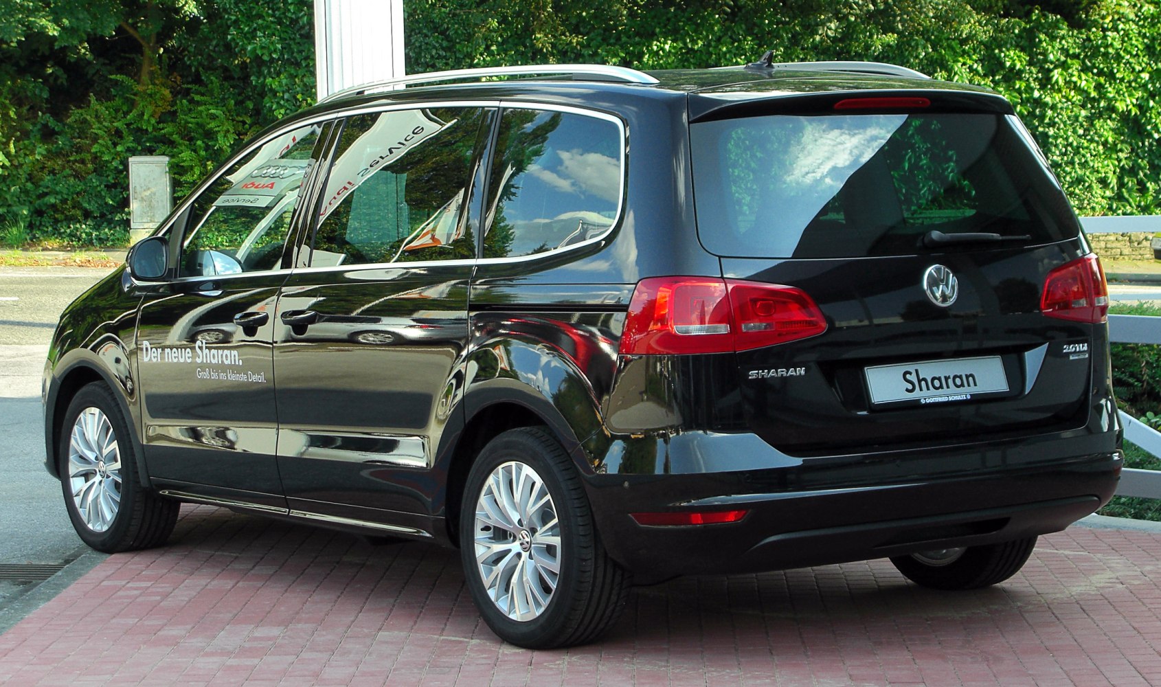 Rear-side view of black MPV showing taillights, alloy wheels, sliding rear door