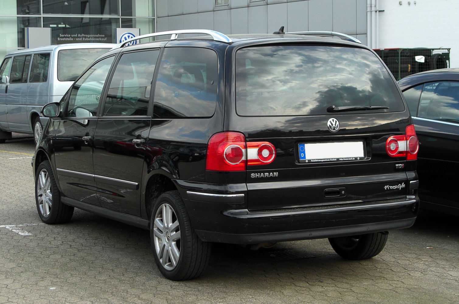 Rear view of a black minivan with distinctive taillights and roof rails