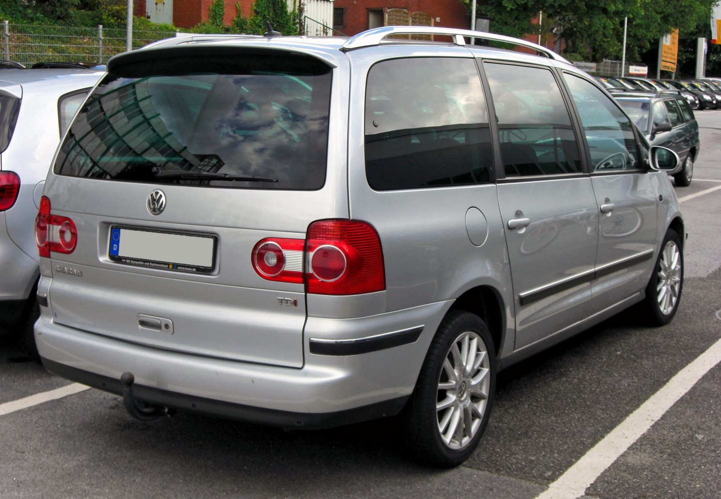 Rear side view of silver minivan with distinctive taillights and roof rails