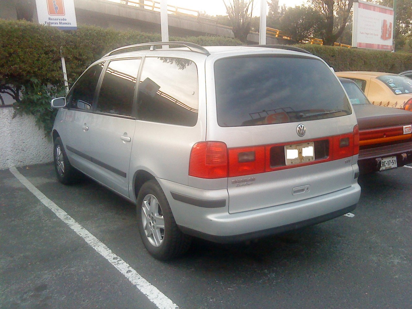 Silver minivan rear with wrap-around taillights and roof rails