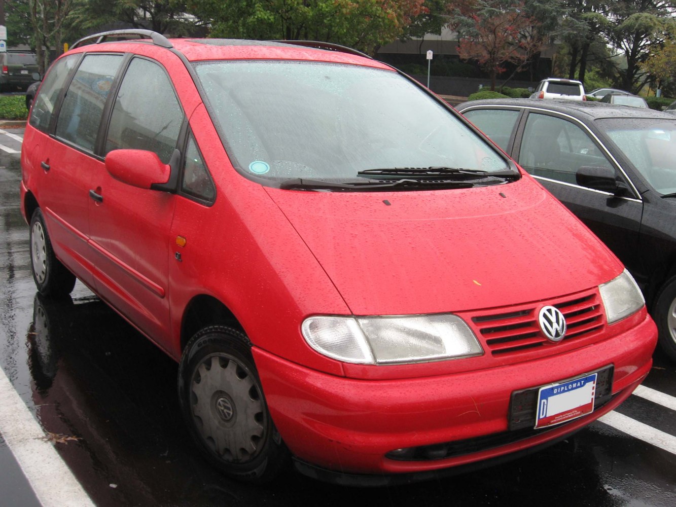 Red minivan front and side view with roof rails in wet parking lot