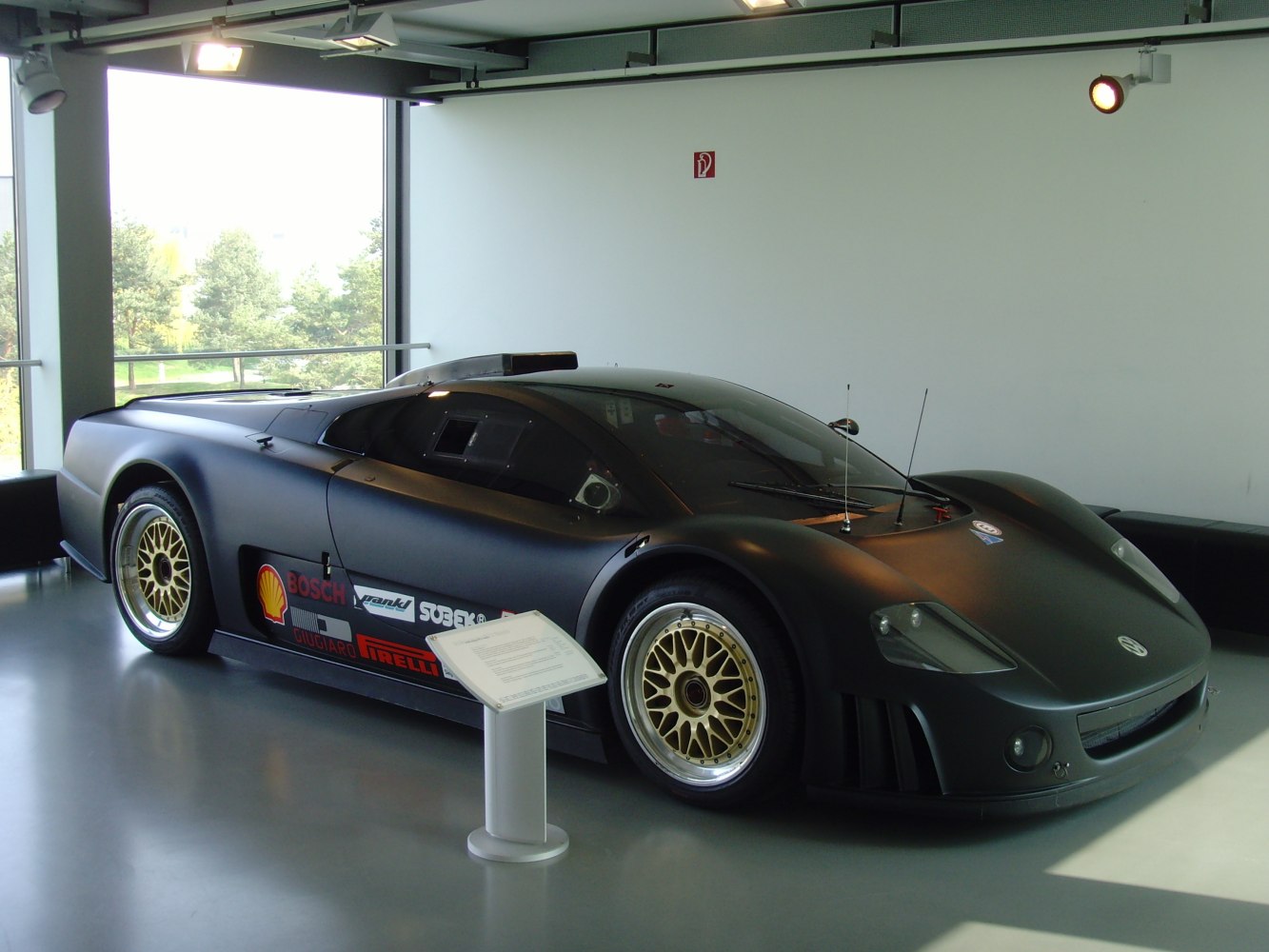 Sleek aerodynamic race car with gold BBS wheels and racing decals