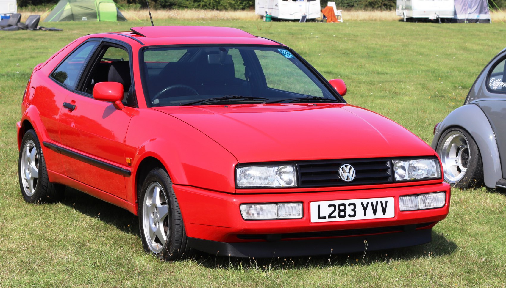 Red sporty coupe with sharp rectangular headlights and black grille.