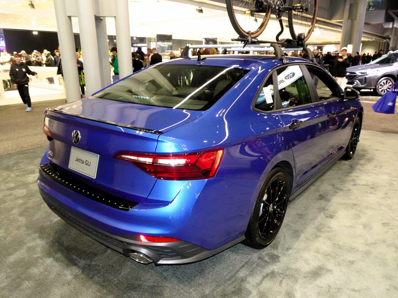 Rear view of blue sedan with black alloy wheels and roof bike rack