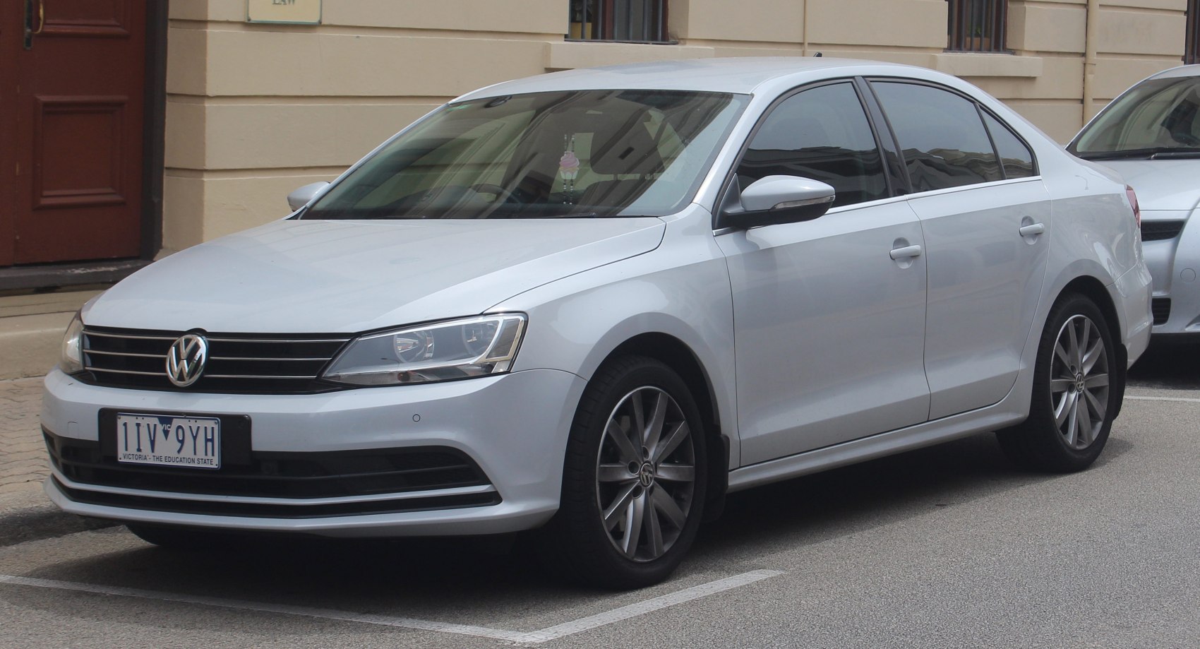 White sedan front grille, headlights, alloy wheels, side profile view
