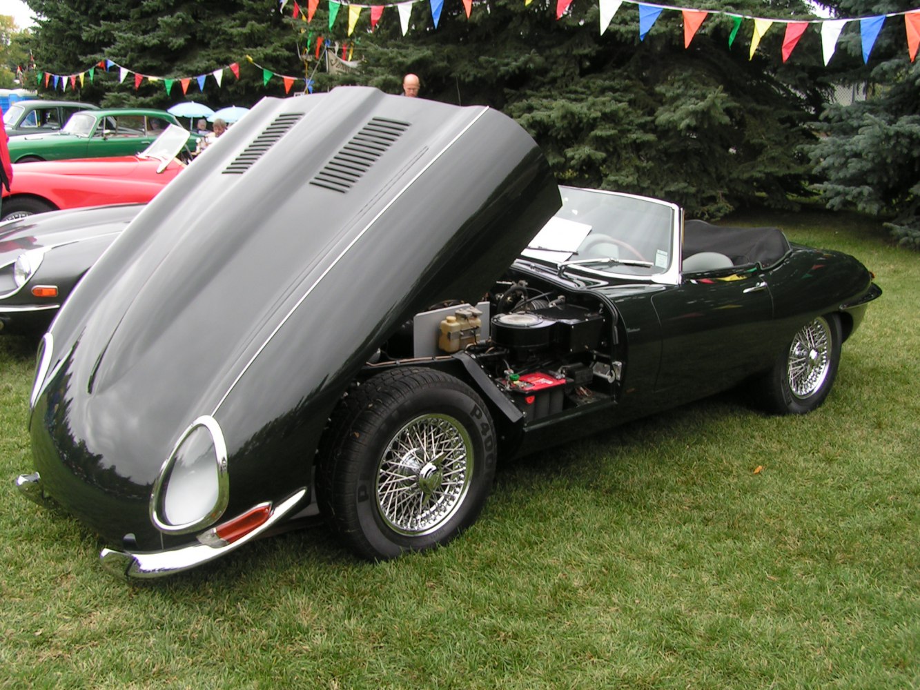 Classic convertible with open hood showcasing engine and wire spoke wheels