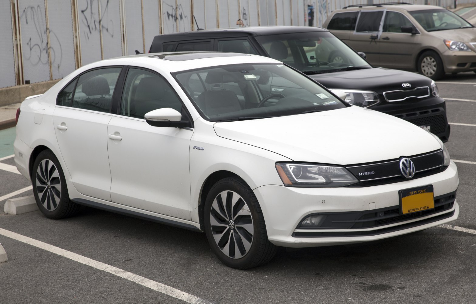 White hybrid midsize sedan front-side view with distinctive wheels