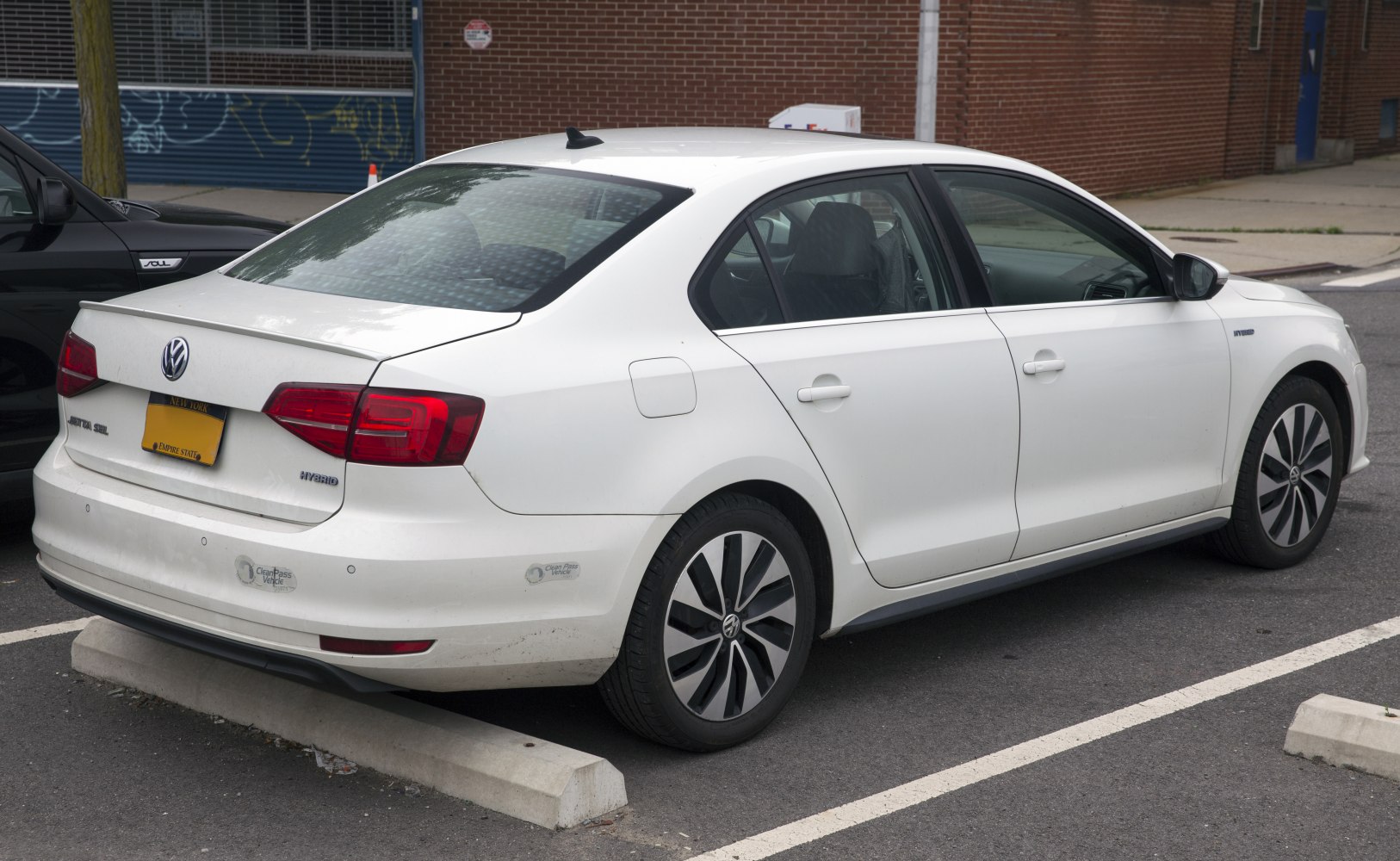 White sedan showing rear side with hybrid badging and modern alloy wheels