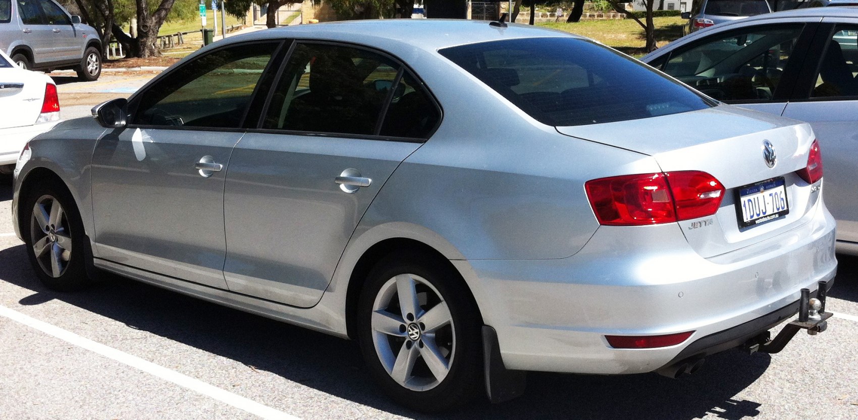 Rear side view of silver sedan with alloy wheels and tow hitch
