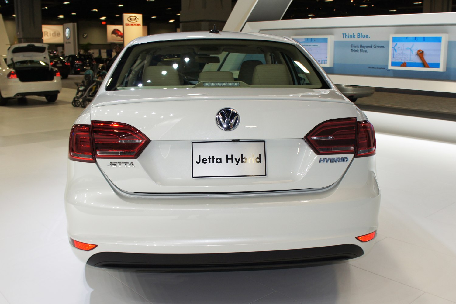 Rear view of a white hybrid sedan with distinct taillights and hybrid badge