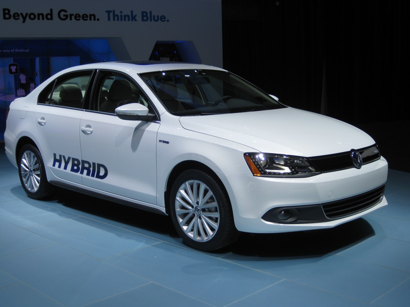 Sleek white hybrid sedan front side with clear headlights and alloy wheels