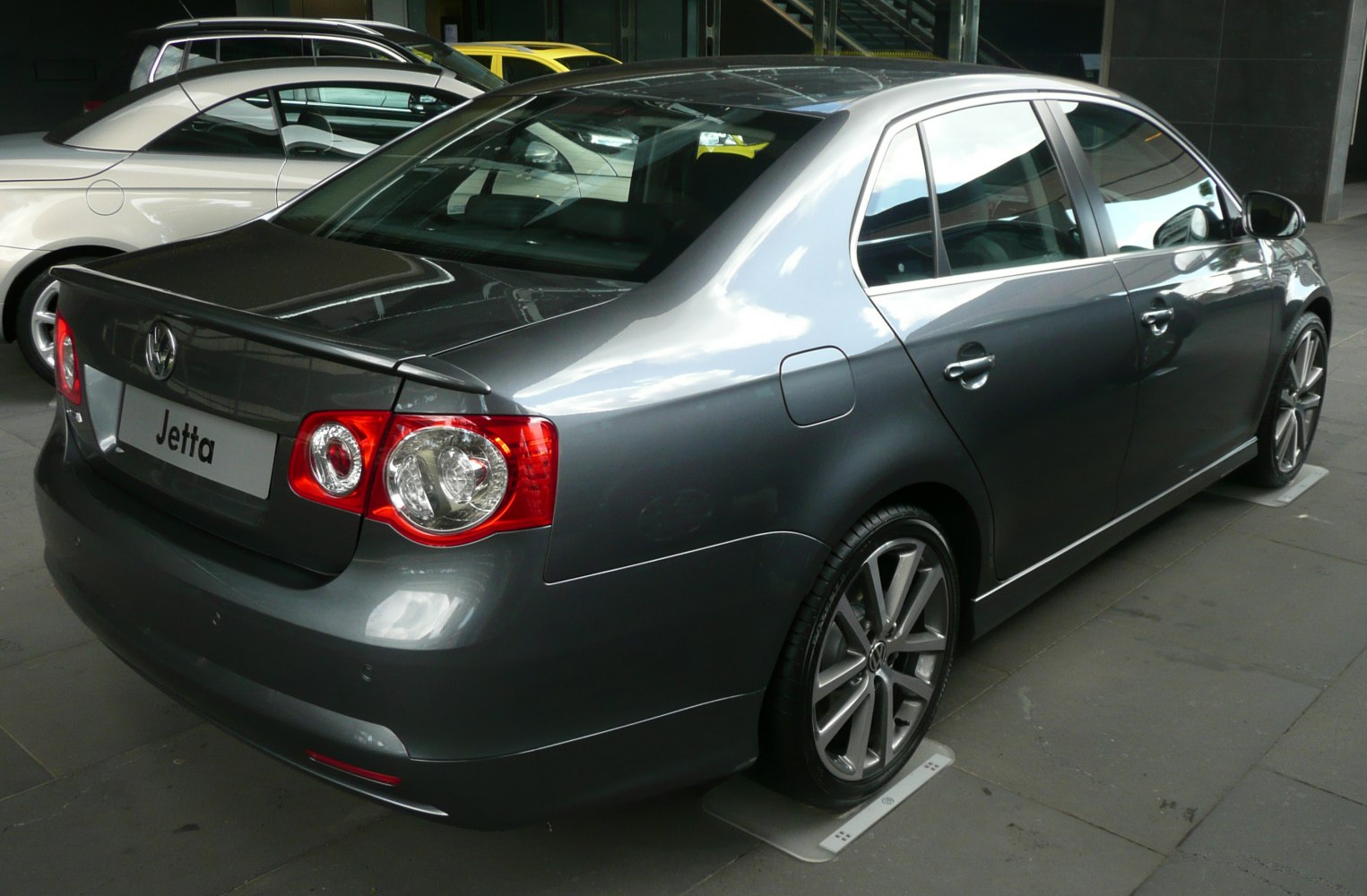 Rear and side view of a sleek, gray sedan with distinctive taillights and sporty alloy wheels