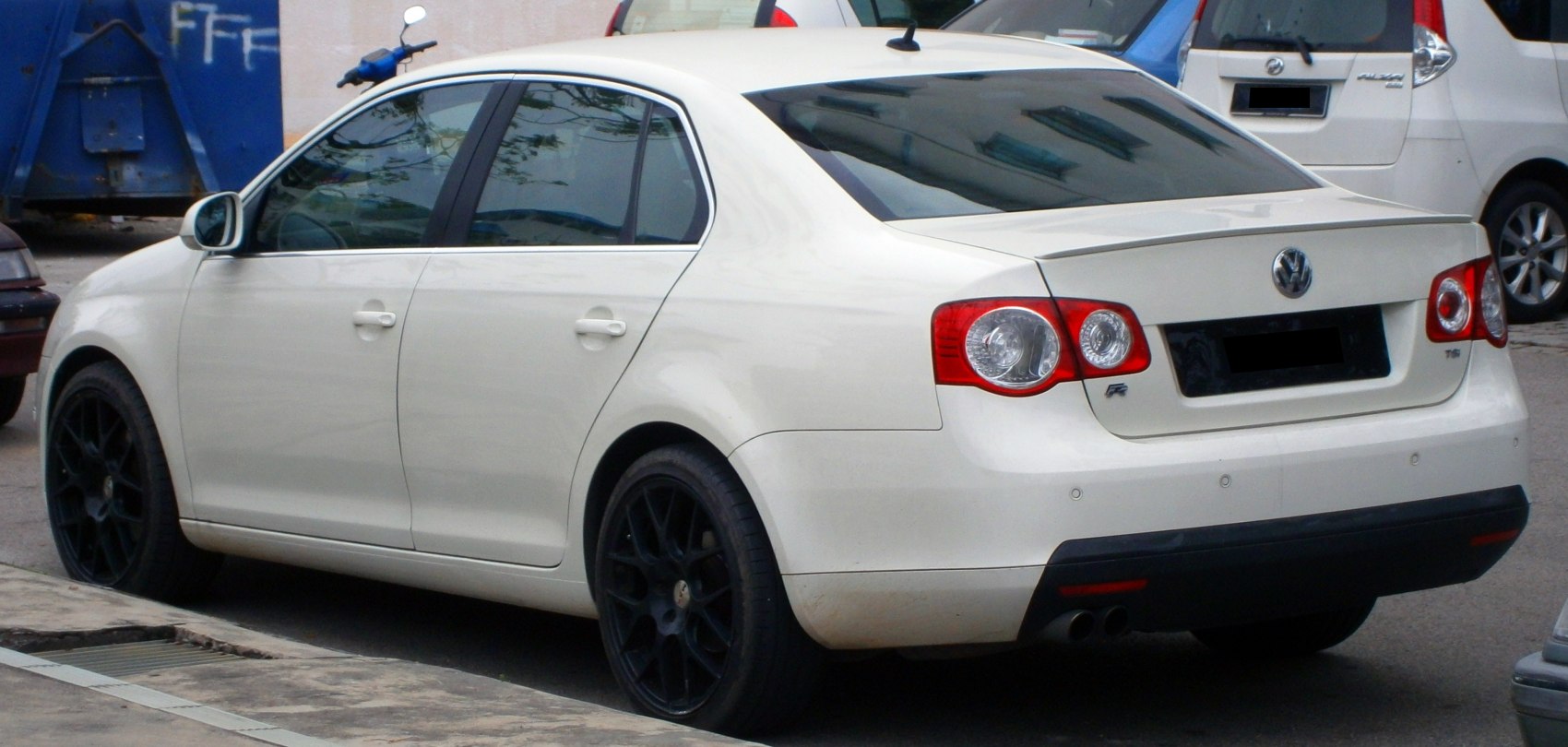 White sedan with black alloy wheels and rear spoiler
