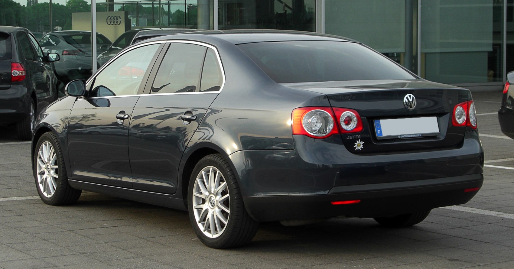 Rear side view of a sedan with distinctive tail lights and alloy wheels.