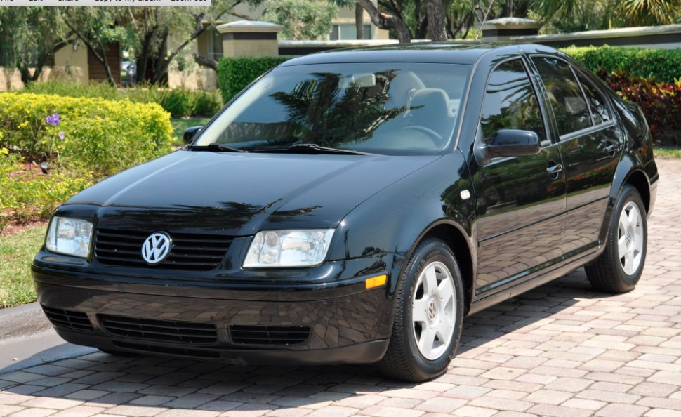 Black sedan with clear headlights and alloy wheels in outdoor driveway setting