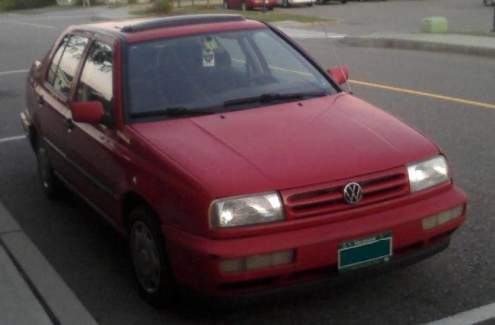 Front-side view of red sedan with headlights and grille