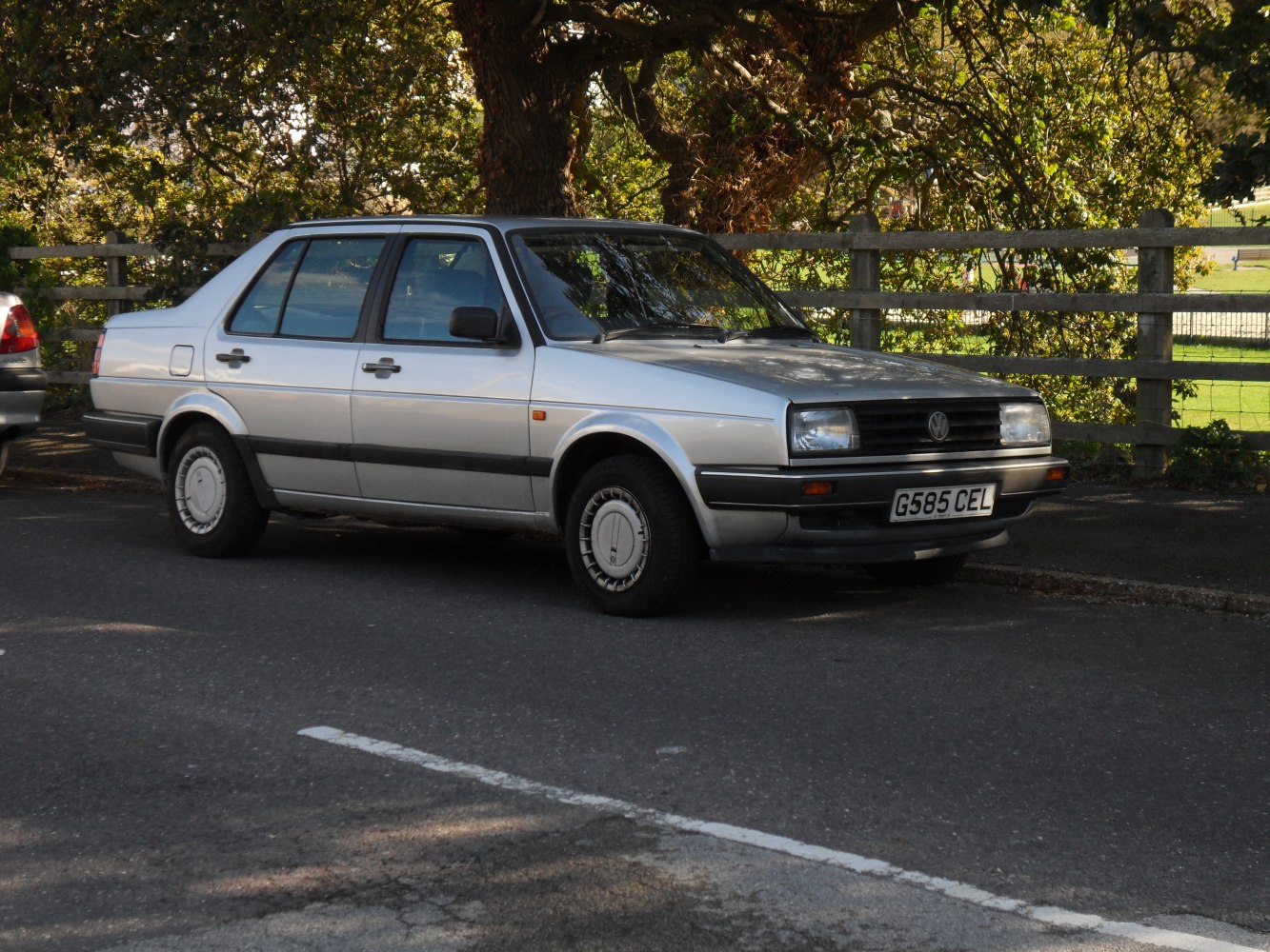 Silver sedan with black trims and classic wheels parked on pavement