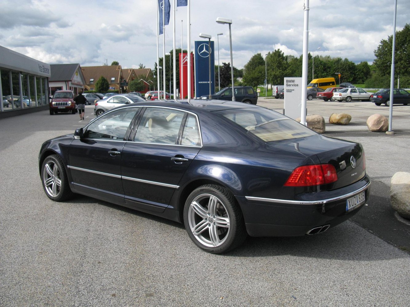 Rear side view of a dark sedan with alloy wheels and prominent taillights