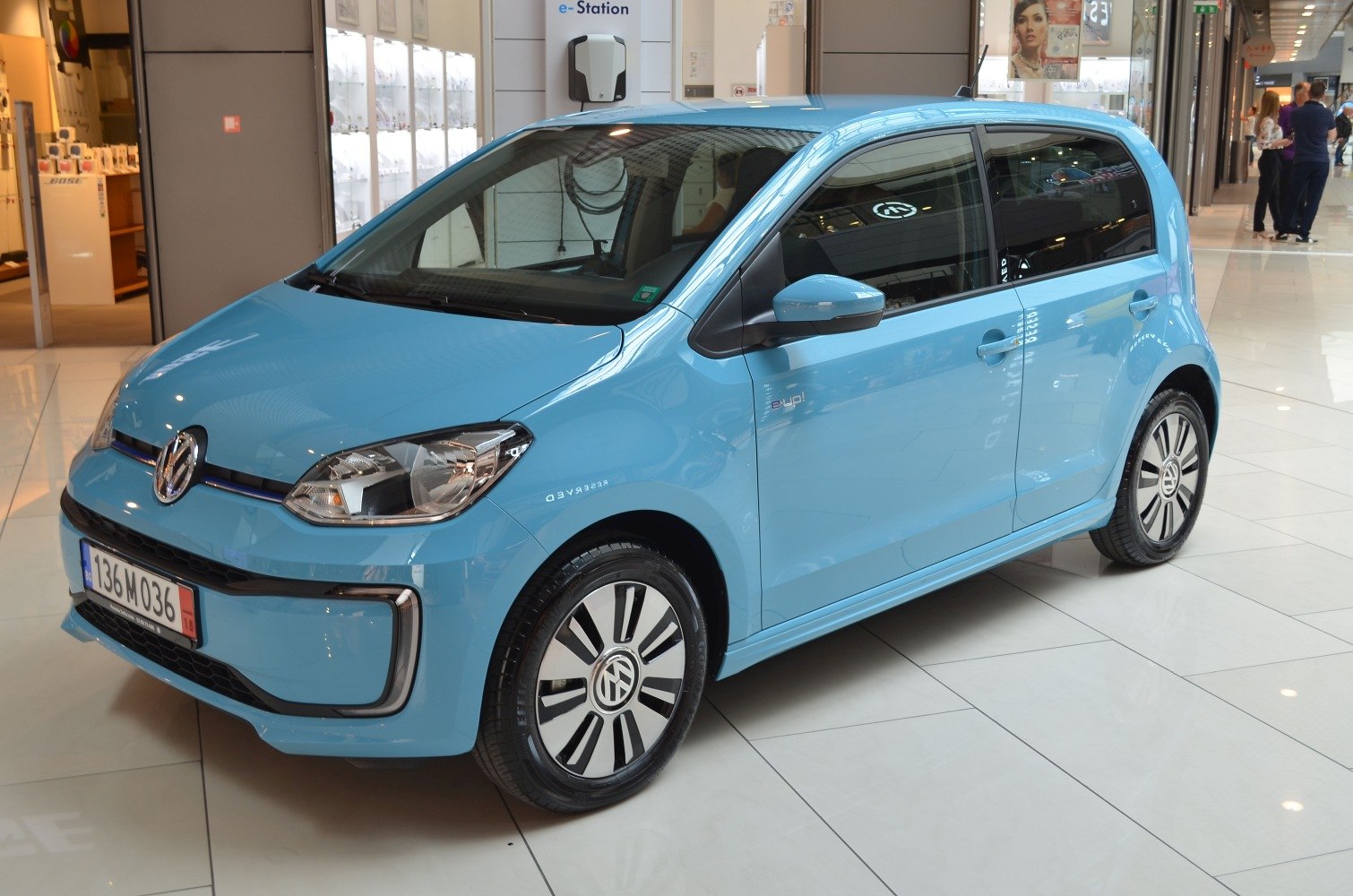 Blue electric compact city car with facelift design and alloy wheels