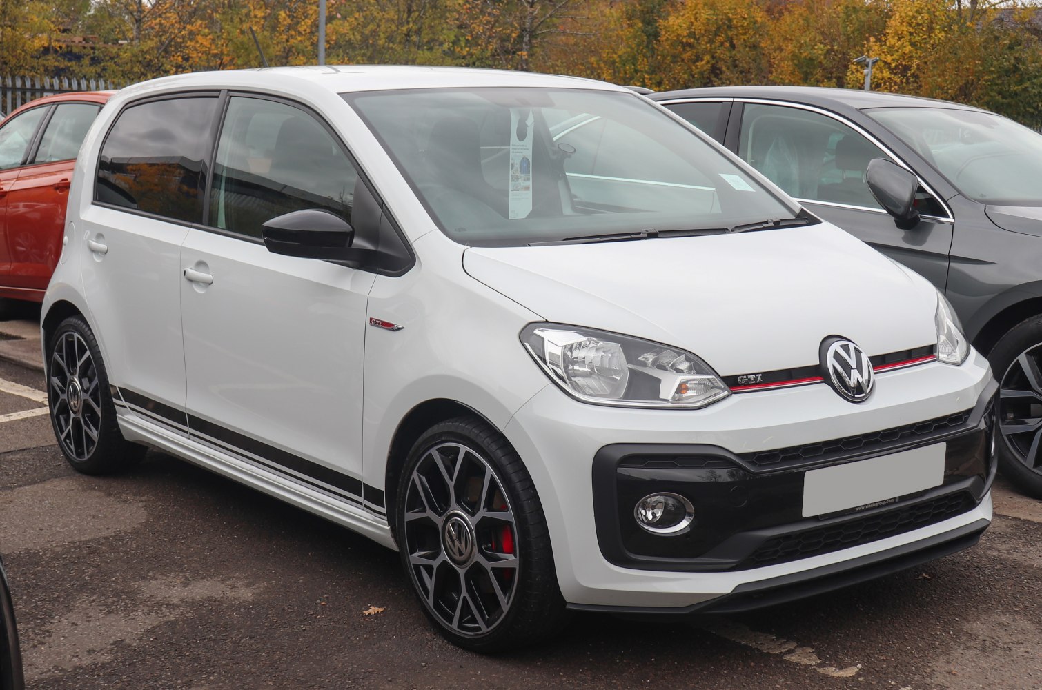 White compact hatchback with sporty wheels and red-accented grille