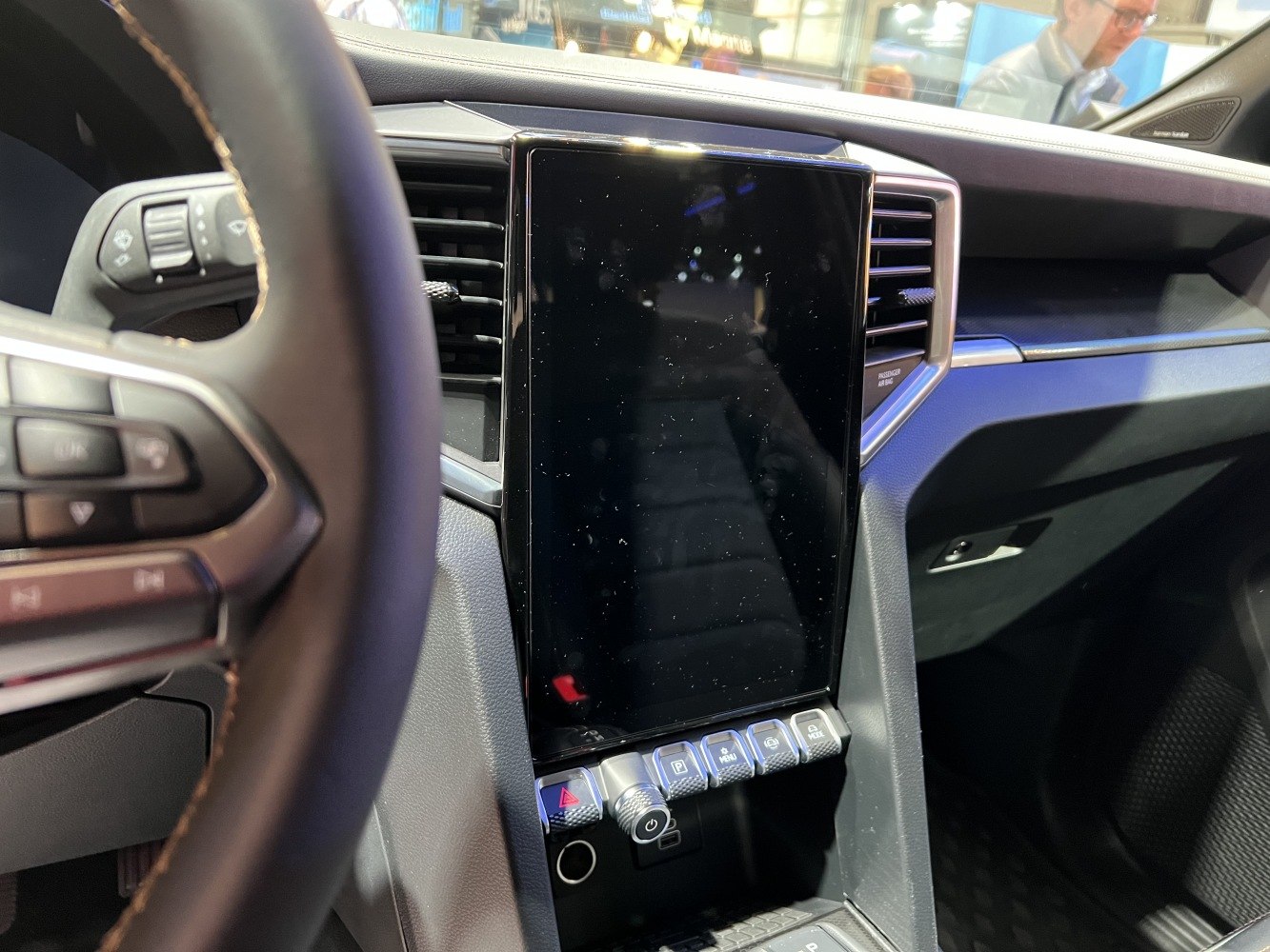 Central touchscreen display and control buttons on vehicle dashboard.