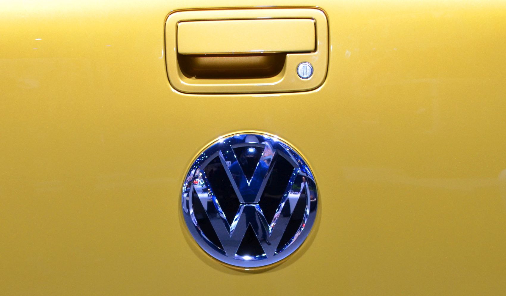 Close-up of rear door handle and Volkswagen badge on yellow vehicle