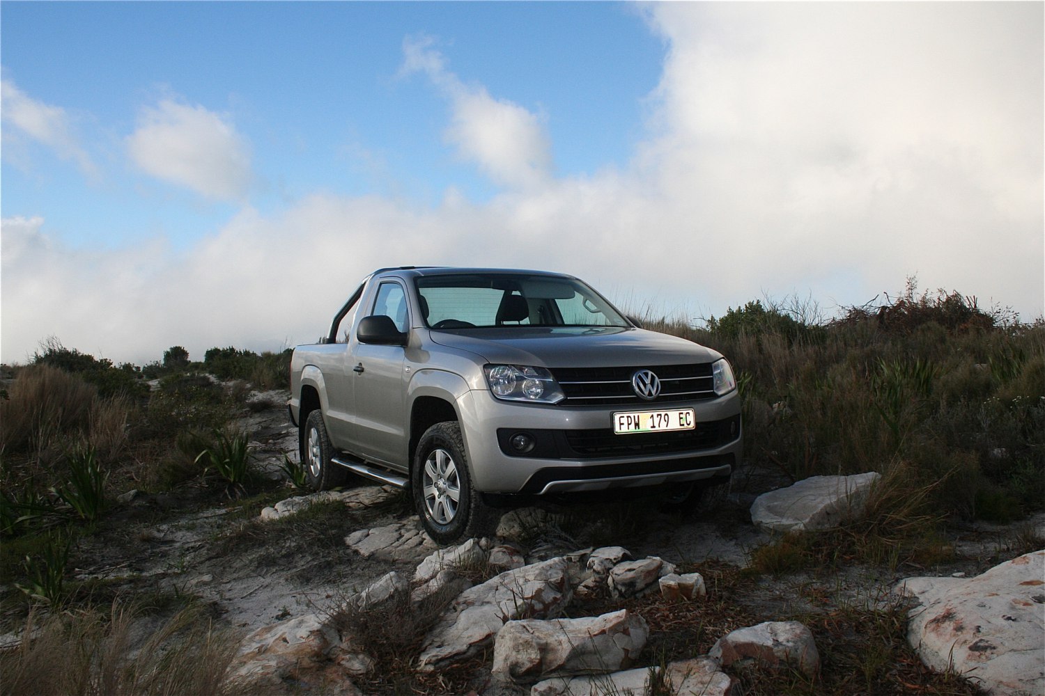 Single cab pickup navigating rocky off-road terrain.