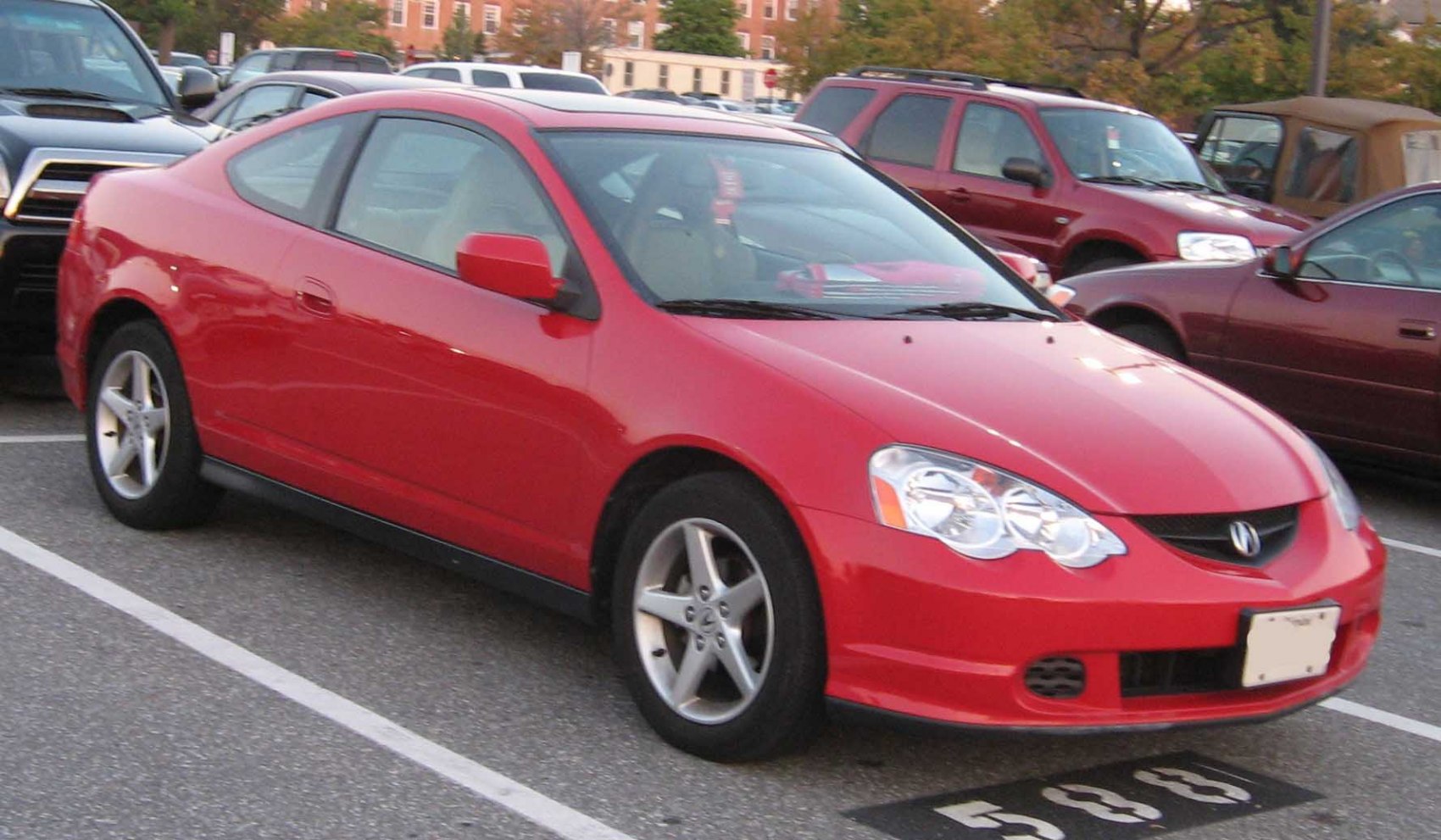 Red two-door coupe with alloy wheels, parked outdoors.