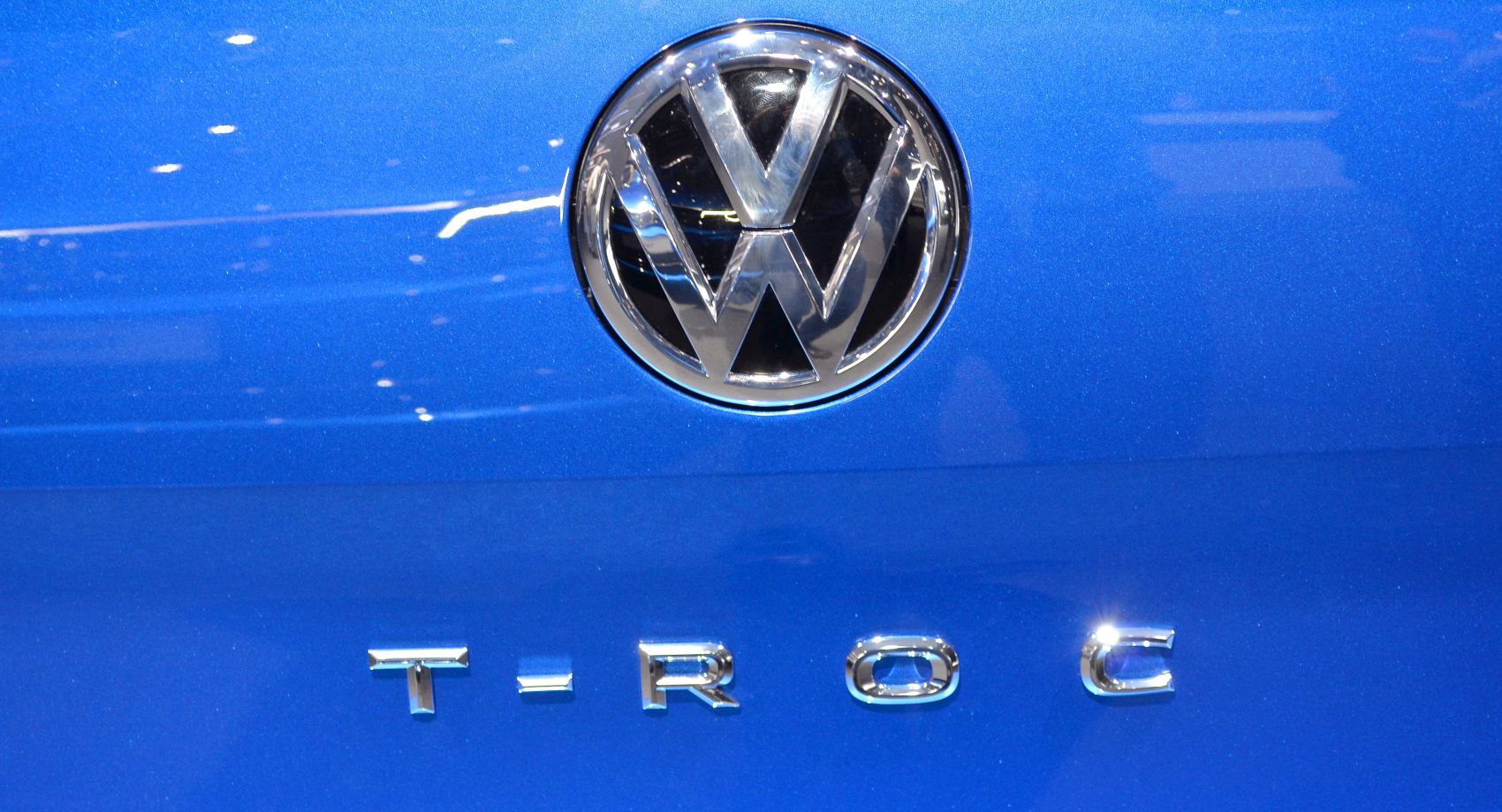 Close-up of Volkswagen emblem and T-Roc badge on blue car paint