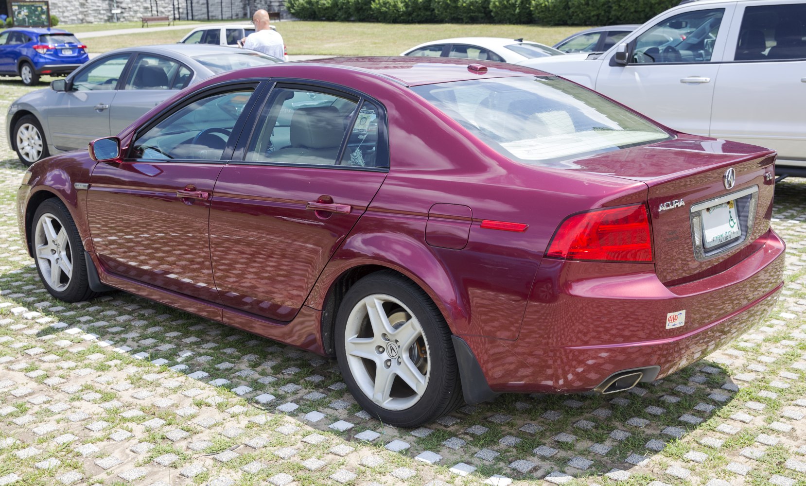 Red sedan rear-side view with alloy wheels and distinctive taillights