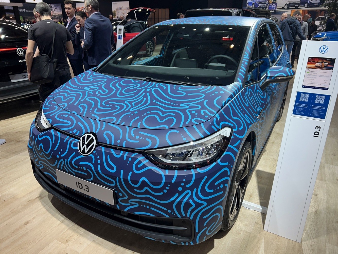 Front view of electric hatchback with blue patterned wrap and LED headlights