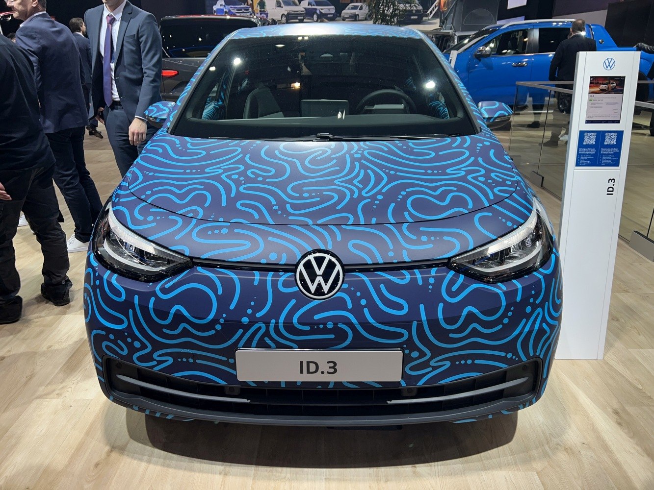 Front view of electric hatchback with blue patterned wrap and LED headlights
