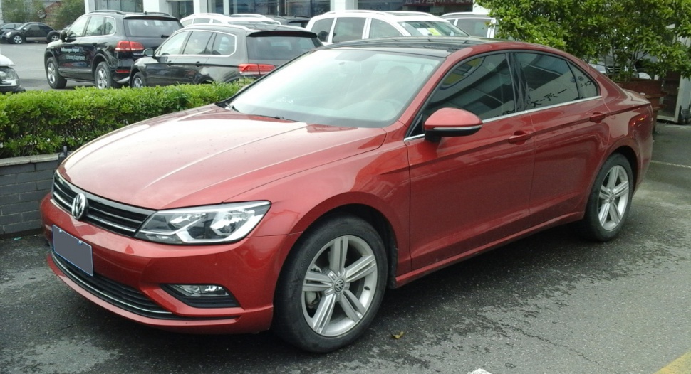 Front side view of red four-door sedan with alloy wheels.
